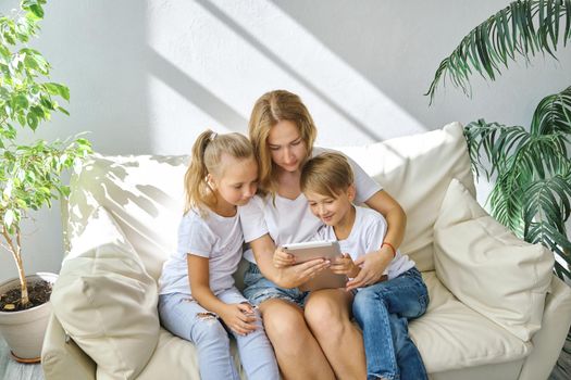 Family. Young mother with kids daughter and boy using digital tablet computer device. Caucasian family at home having online video conference call, rejoice and laugh.