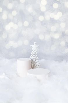 Podiums mok-up for cosmetics in the snow with a christmas tree on a bokeh background vertical format.