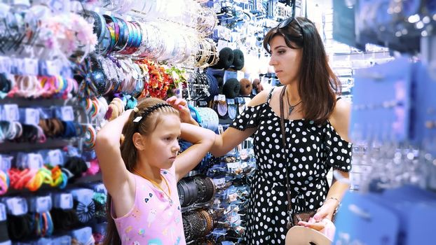 woman's hair accessories in shopping mall. girl, kid and mum choose hairpins, rubber bands, hair band, in the store. High quality photo