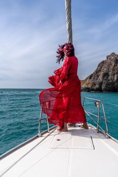 Attractive middle-aged woman in a red dress on a yacht on a summer day. Luxury summer adventure, outdoor activities