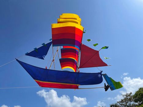 flying ship, rainbow colored ship kite flies on the blue sky and cloud in the beach