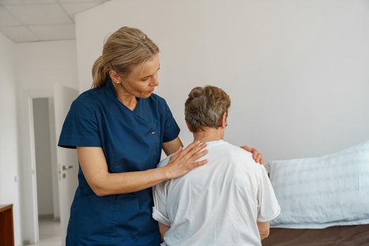 Professional doctor in uniform examines the patient during a visit to hospital ward in clinic