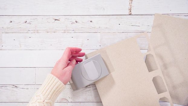 Flat lay. Step by step. Cutting out gift tags from brown paper with a paper punch.