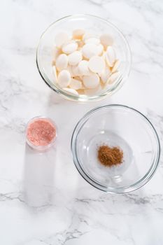 Measured ingredients in glass mixing bowls to make a chocolate gingerbread man.