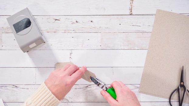 Flat lay. Step by step. Cutting out gift tags from brown paper with a paper punch.