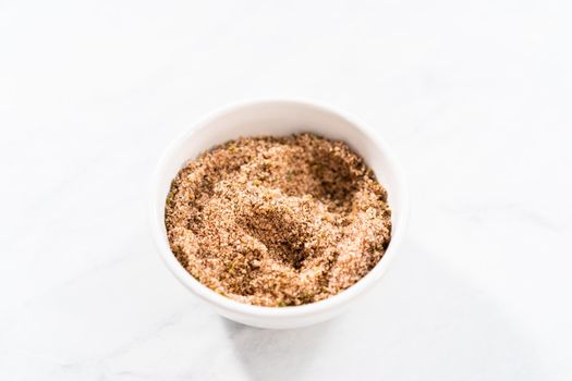 Mixing ingredients in a small glass mixing bowl to prepare chili lime salt for Mexican watermelon pops.