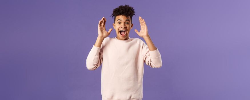 Portrait of happy surprised young man, celebrating birthday, open his eyes to see something really awesome, receive incredible gift, being astounded and speechless from joy and happiness.