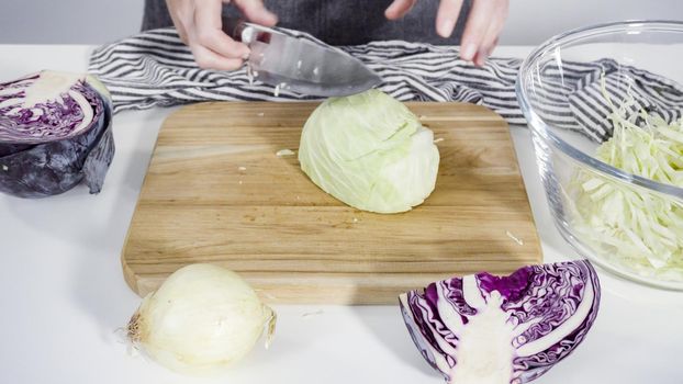 Step by step. Shredding organic cabbage on a wood cutting board.