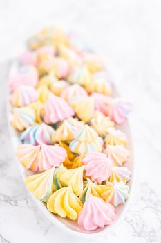 Multicolored unicorn meringue cookies on a white serving plate.