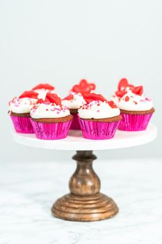 Red velvet cupcakes with cream cheese frosting and decorates with heart and kiss shaped red chocolates.