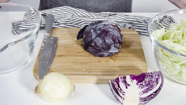 Step by step. Shredding organic cabbage on a wood cutting board.