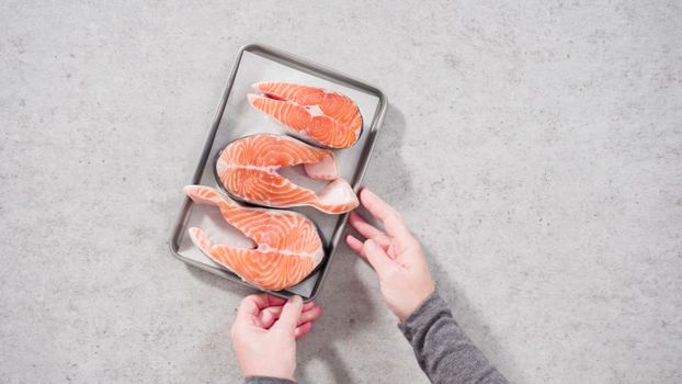 Farm-raised salmon steaks on a cooking tray with a parchment paper.