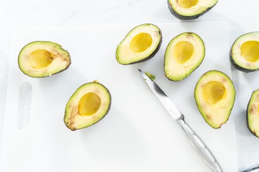 Cutting ingredients on a white cutting board to make classic guacamole dip.