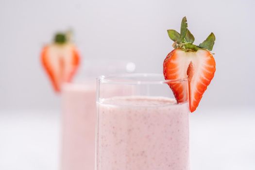 Freshly made healthy breakfast strawberry banana smoothie garnished with fresh strawberry and paper straw.