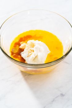 Mixing ingredients in a large glass mixing bowl to bake red velvet bundt cake with cream cheese glaze.