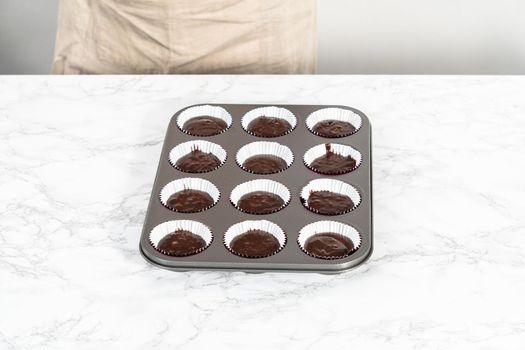 Baking chocolate cupcakes. Scooping chocolate cupcake batter into a cupcake pan.