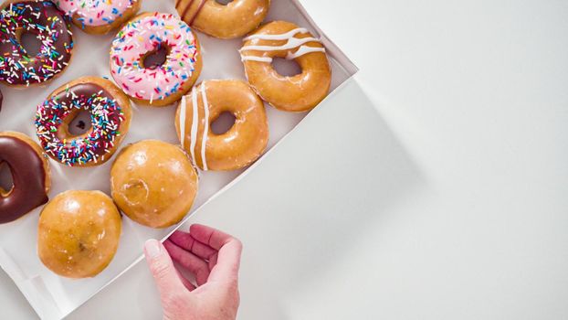 Flat lay. Variety of store-bought doughnuts in a white paper box.