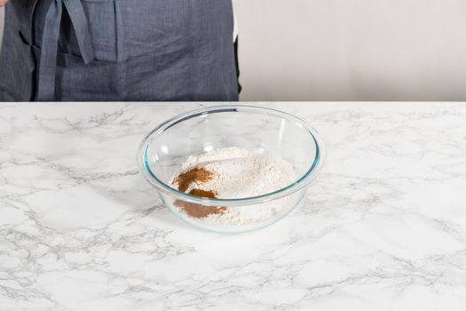 Mixing dry ingredients in a large glass mixing bowl to bake eggnog cookies with a chocolate gingerbread man.