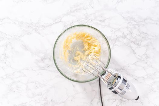 Flat lay. Mixing ingredients in a large glass mixing bowl to prepare cream cheese drizzle sauce.