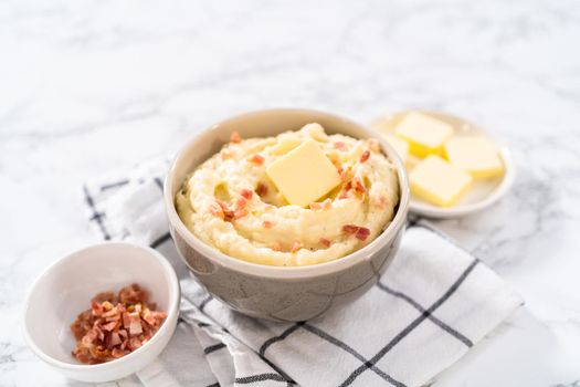 Mashed potatoes. Creamy mashed potatoes garnished with a slice of butter and bacon bits in a bowl.