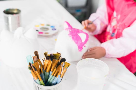 Little girl painting Halloween pumpkin with acrylic paint.