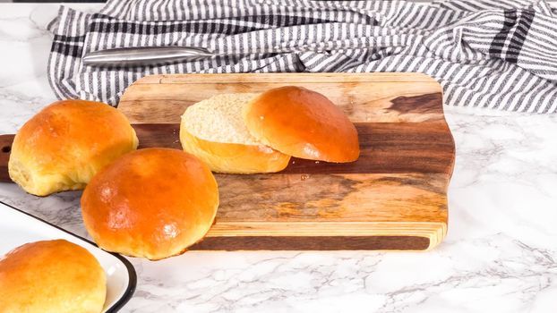 Step by step. Slicing freshly baked brioche bun on a wood cutting board.