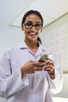 Its how I confirm all my appointments with my patients. Portrait of a young female dentist texting on her cellphone in her office