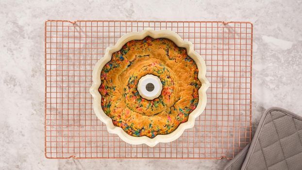 Flat lay. Step by step. Cooling freshly baked funfettti bundt cake on a wire rack.