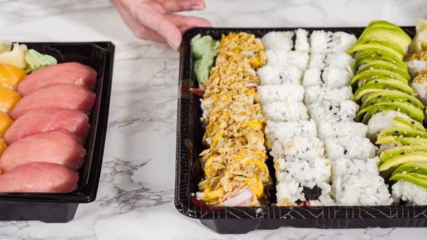 Pre-packaged variety of sushi and sushi rolls in a plastic tray.