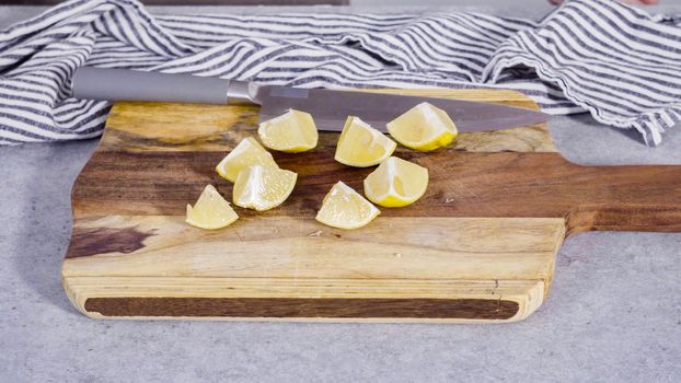 Cutting organic lemon on a wood cutting board.