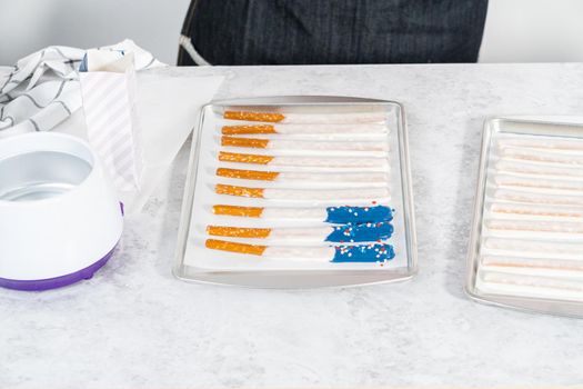 Dipping pretzel rods into the melted chocolate to prepare chocolate dipped pretzel rods for the July 4th celebration.