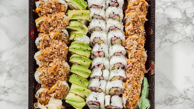 Flat lay. Pre-packaged variety of sushi and sushi rolls in a plastic tray.