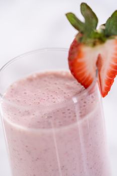 Freshly made healthy breakfast strawberry banana smoothie garnished with fresh strawberry and paper straw.