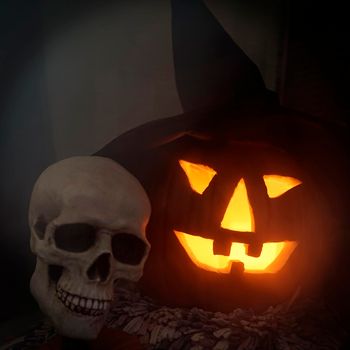 For Halloween: nightmare skull and lighted pumpkin with a witch hat in the fog