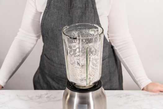 Blending ingredients for healthy breakfast strawberry banana smoothie in a kitchen blender.