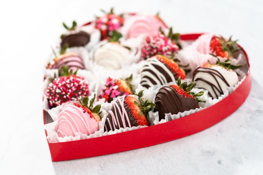 Heart shaped box with assorted chocolate covered strawberries on a white background.