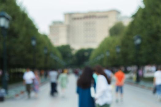 Abstract blurred defocused background with people walking on the street. Unrecognizable faces.