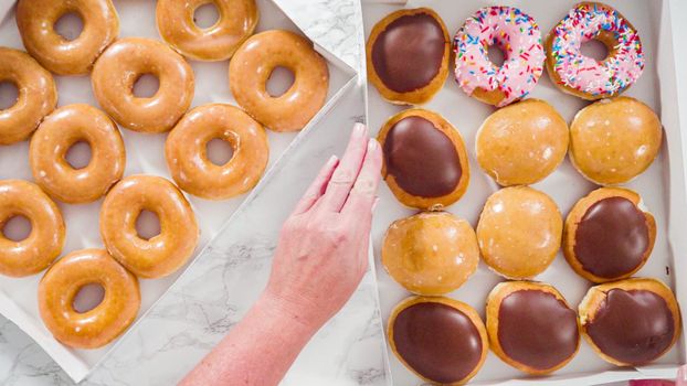 Flat lay. Variety of store-bought doughnuts in a white paper box.