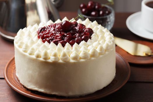 Biscuit cake, cherry souffle with cream cheese and cherry confiture on wooden background. Close-up