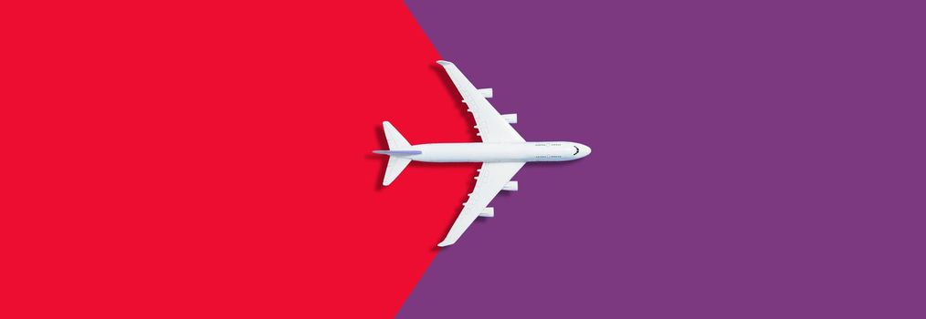 Flat lay of miniature toy airplane on red and purple background. High quality photo