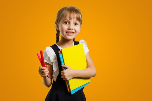 Cropped close up shot of a happy smart caucasian teenager schoolgirl pupil student wearing bag going back to school for new academic educational year isolated in yellow background