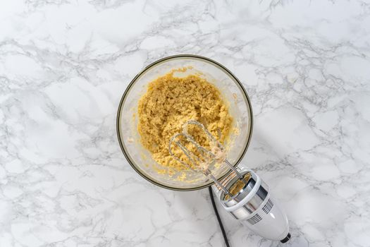 Flat lay. Mixing ingredients with a hand mixer to bake eggnog cookies with a chocolate gingerbread man.