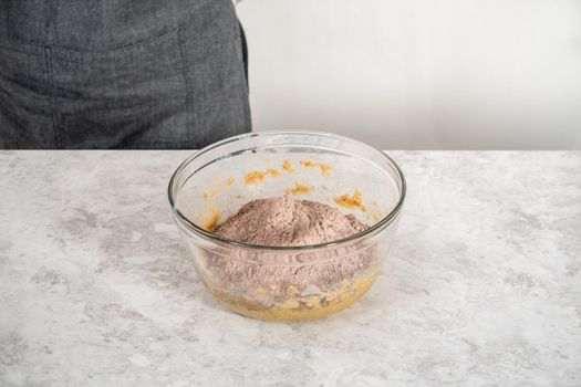 Mixing ingredients in a large glass mixing bowl with a kitchen mixer to bake chocolate cookies with peppermint chips.