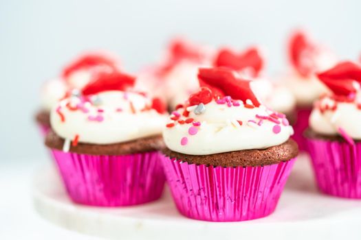 Red velvet cupcakes with cream cheese frosting and decorates with heart and kiss shaped red chocolates.