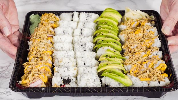 Pre-packaged variety of sushi and sushi rolls in a plastic tray.