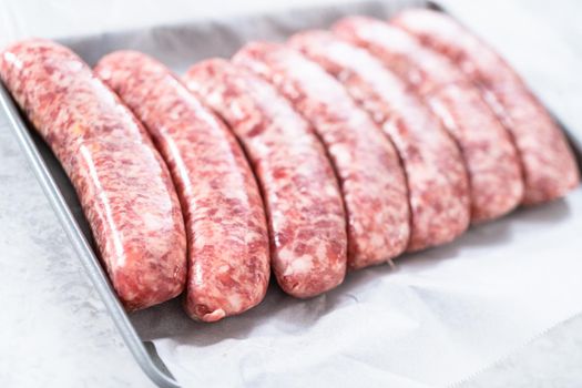 Raw beer bratwursts in the row on a small tray.