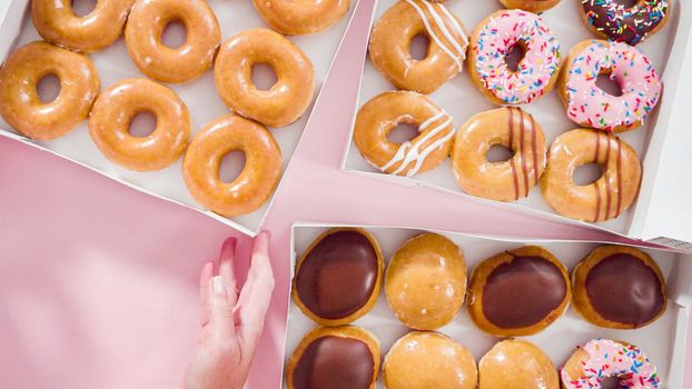 Flat lay. Variety of store-bought doughnuts in a white paper box.