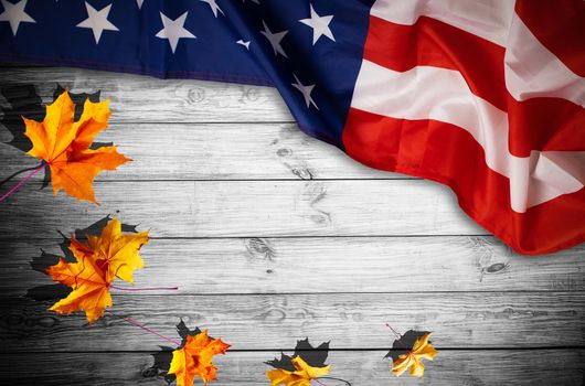 little flag of USA with maple leaves on wooden table. Above view