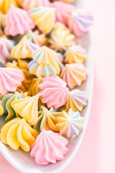 Multicolored unicorn meringue cookies on a white serving plate.