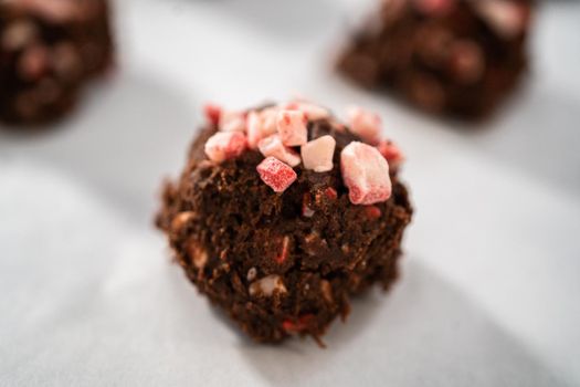 Scooping chocolate cookie dough with dough scoop to bake chocolate cookies with peppermint chips.